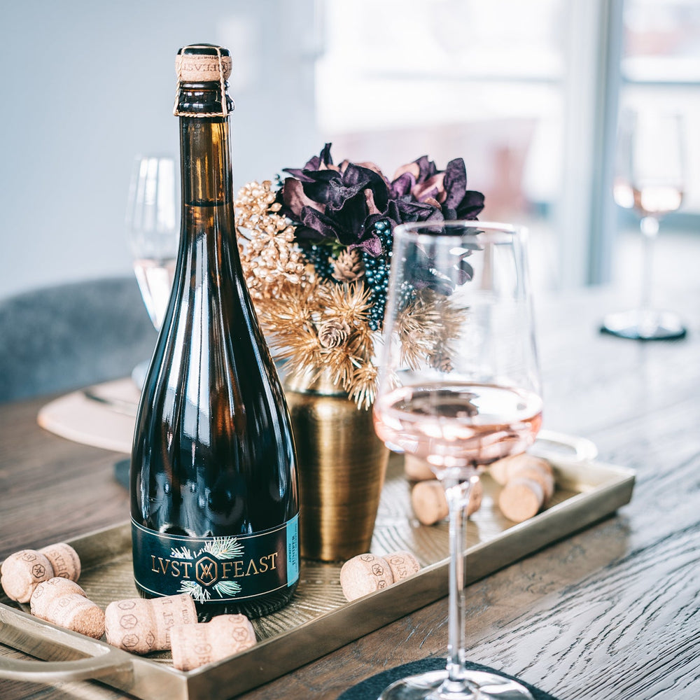 
                  
                    Eine Flasche JUNIPER von LUST & FEAST auf einem dekorierten Tisch mit einem Weinglas und Korken edel anmutend
                  
                